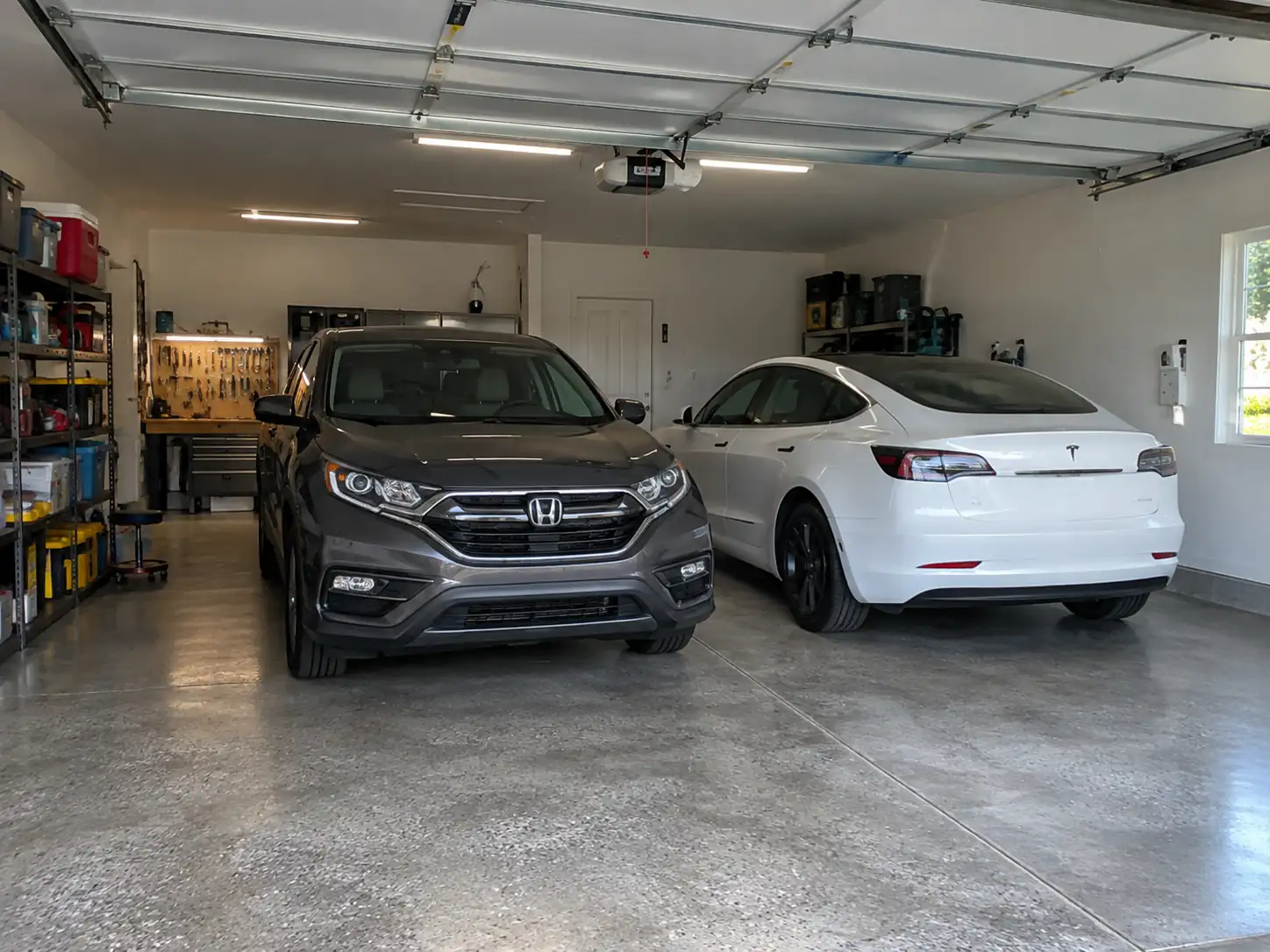 Cost to Build a 2 Car Garage in 2026: Full Price Breakdown 4 Finished two-car garage interior with two parked vehicles, storage shelves, and overhead lighting